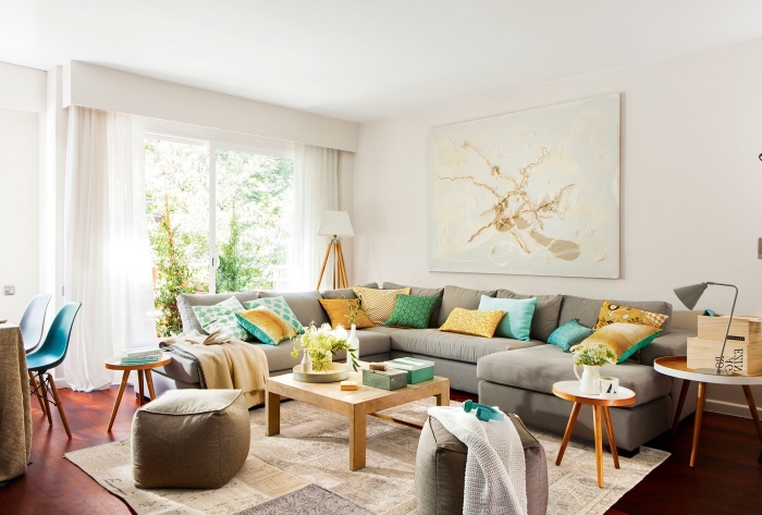 les couleurs qui vont ensemble dans un salon cozy, pièce blanche avec parquet foncé et grand canapé gris clair décoré de coussins en couleurs jaunes et vertes