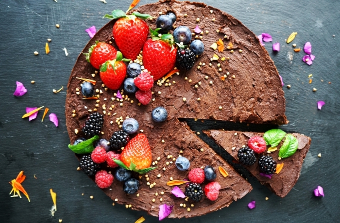 recette vegan de gateau sans farine au glaçage riche de trois chocolats décoré de fruits rouges et de fleurs comestibles