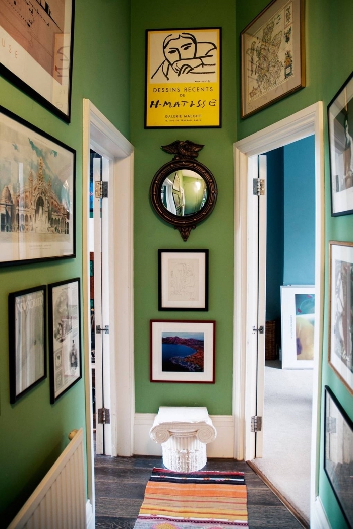 déco couloir étroit peint en vert avec des murs en cadres photos variés et des portes blanches