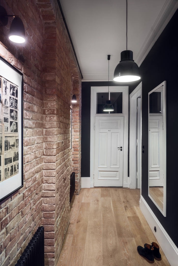 deco couloir de style loft industriel au mur en briques qui s'accorde parfaitement avec le noir du mur opposé et l'éclairage industriel
