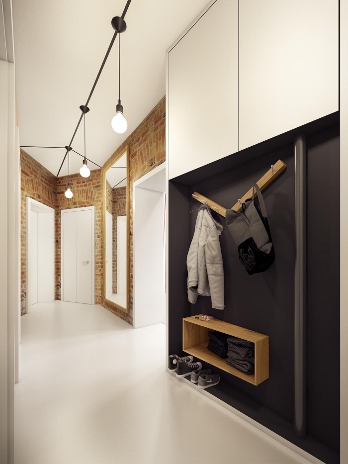 un meuble entrée couloir en noir et blanc mat qui s'inscrit parfaitement dans un couloir de style scandinave aux murs en papier peint imitation briques