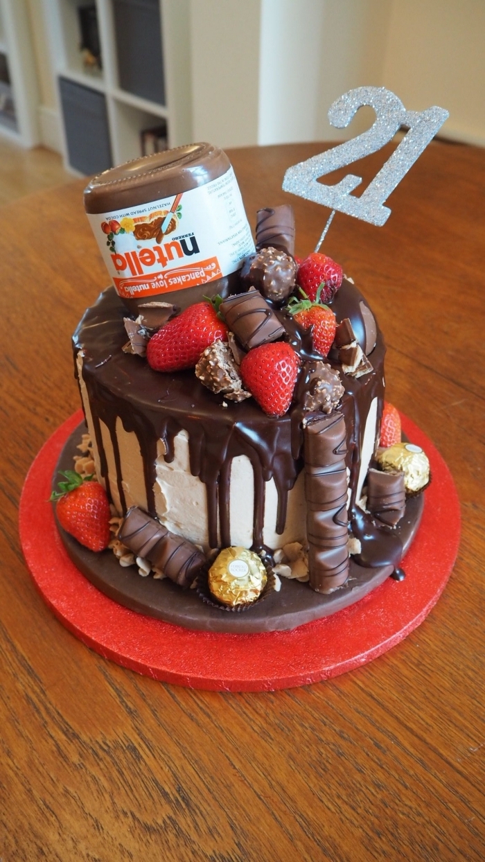 idée de gateau anniversaire original au glaçage coulant de chocolat avec un joli déco de faux pot de nutella, de barres chocolatées et de fraises
