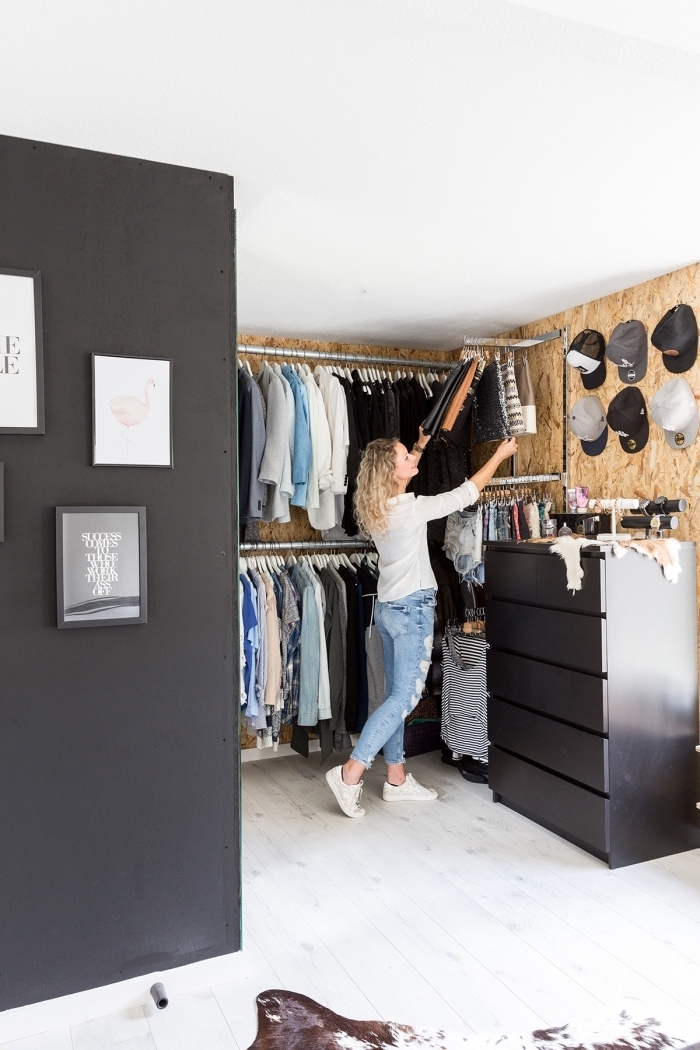 faire son dressing soi même, une pièce en dressing aux murs de liège avec des barres de penderie métalliques, des crochets muraux et une commode noire à tiroirs