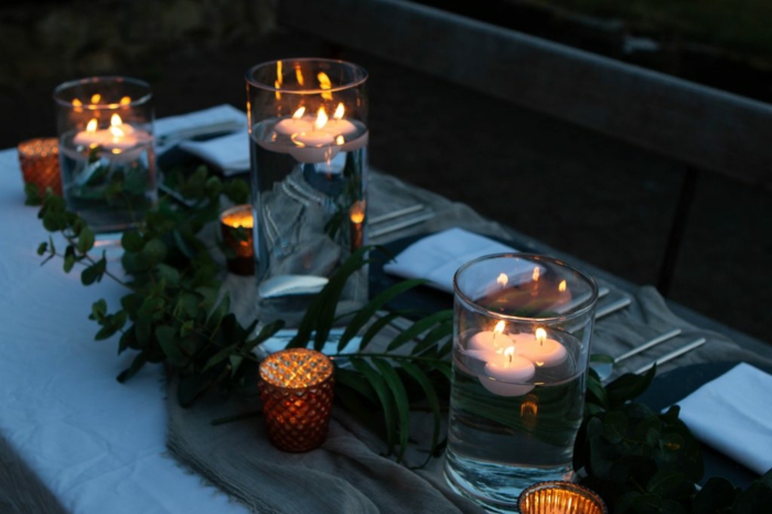 chemin de table jetable en toile de jute, bougeoirs originaux, vases avec bougies flottantes, guirlande de feuilles vertes