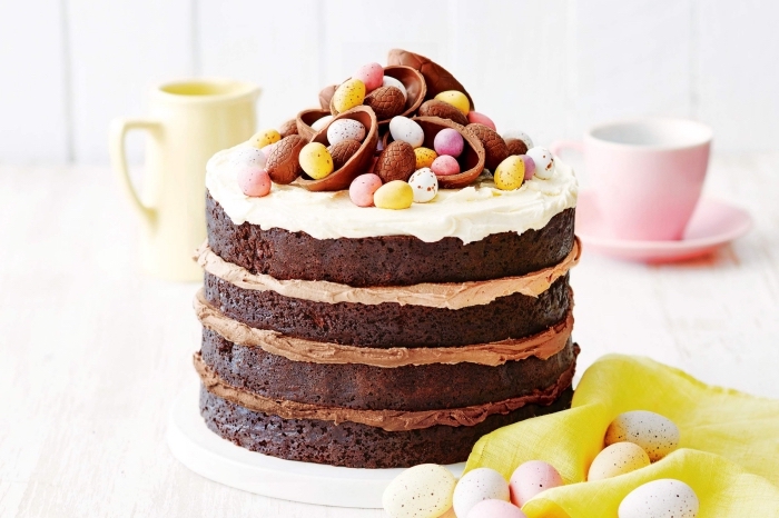 idée de gateau anniversaire adulte composé de quatre génoises au chocolat recouvertes de crème pâtissière au nutella et au chocolat blanc, le tout avec un joli décor d'oeufs au chocolat