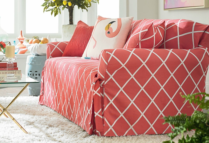 sofa tapissé, tapis blanc, table basse en verre et métal doré, coussins flamingue, arbres décoratifs