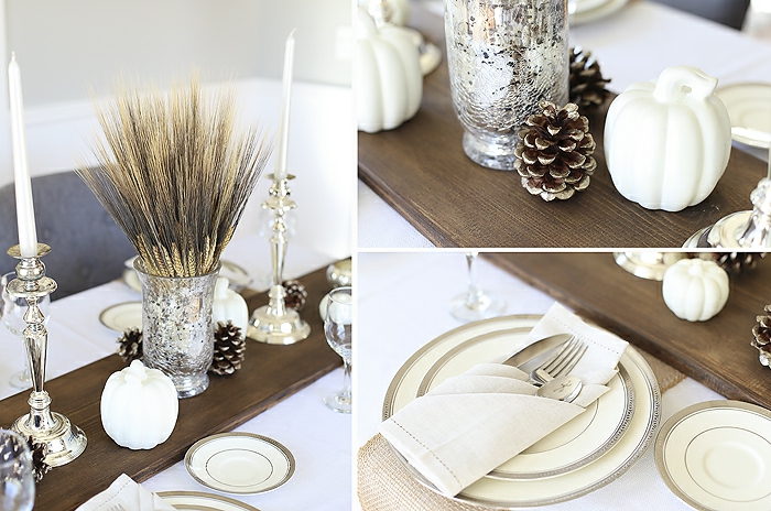 planche de bois peinte, assiettes aux rebords argentés, pommes de pin, vase avec brins de fleurs sèches, citrouilles peintes