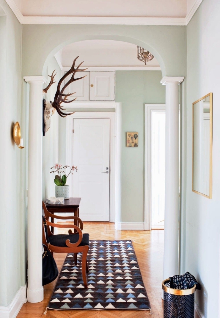 les murs vert menthe à l'eau très clair s'associe à merveille avec le parquet en bois bons et la boiserie peinte en blanc pour créer une ambiance chaleureuse dans le couloir, quelle couleur peindre un couloir avec beaucoup de portes