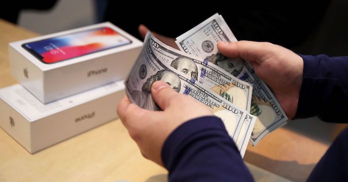 photo d'un achat d'iphone en dollar pour illustrer la baisse du prix du smartphone Apple suite à une chute des ventes