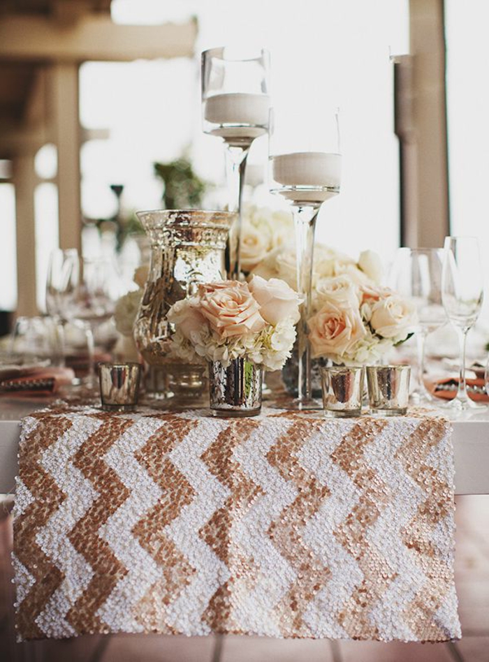 chemin de table blanc aux motifs graphiques dorés, verres remplis de roses crème, porte-bougies hauts