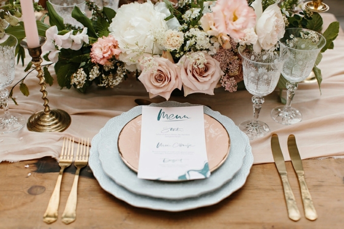 chemin de table rose, deux assiettes blanches et une cuivrée, centre de table mariage roses et feuillage