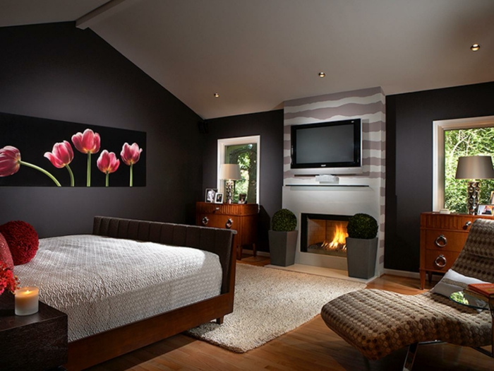 tableau tulipes au mur, cheminée, grand fauteuil tressé, lit en bois, couleur mur chambre noir et blanc