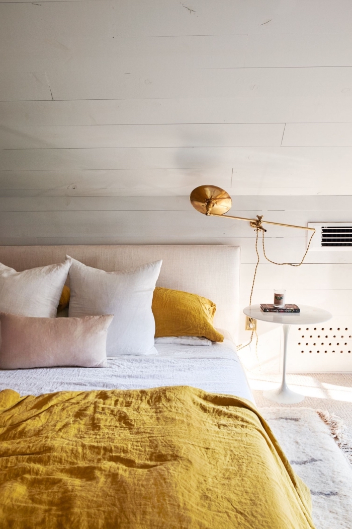 exemple chambre à coucher blanche sous pente, modèle grand lit avec tête de lit beige et couverture de couleur moutarde
