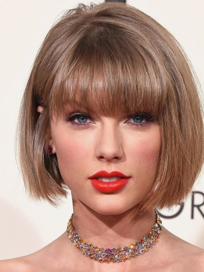 carré plongeant asymétrique de Taylor Swift, lèvres rouges, eyeliner noir, frange droite, cheveux couleur blond cendré