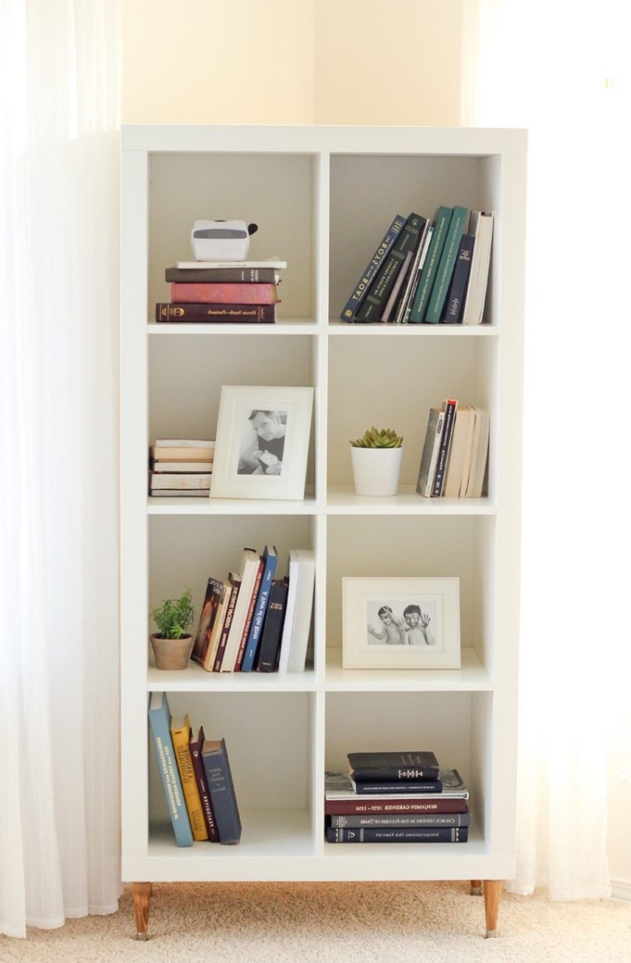 une étagère kallax avec pieds en bois rajoutés qui sert de bibliothèque, idée pour relooker un meuble à petit prix