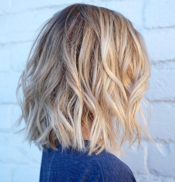 cheveux blond coupés en carré avec effet coiffé décoiffé et voume sur les cotés, blouse couleur bleue