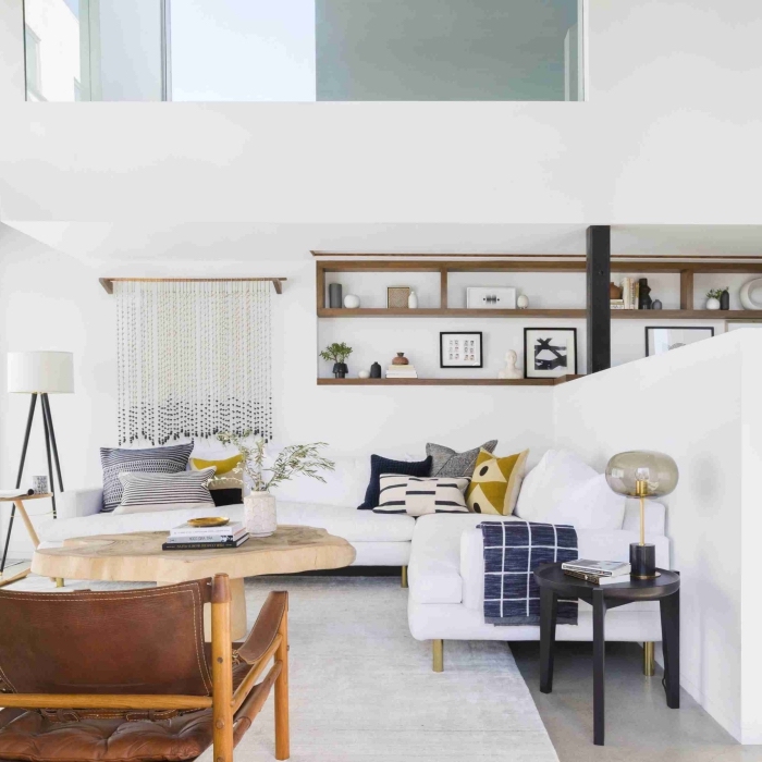 déco minimaliste aux murs blancs et meubles de bois, modèle de grand canapé d'angle décoré avec coussins