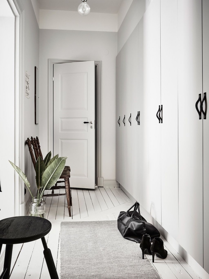 couloir de style scandinave aux murs blancs avec des touches de noir sur le mobilier, meuble couloir entrée avec rangements intégrés 