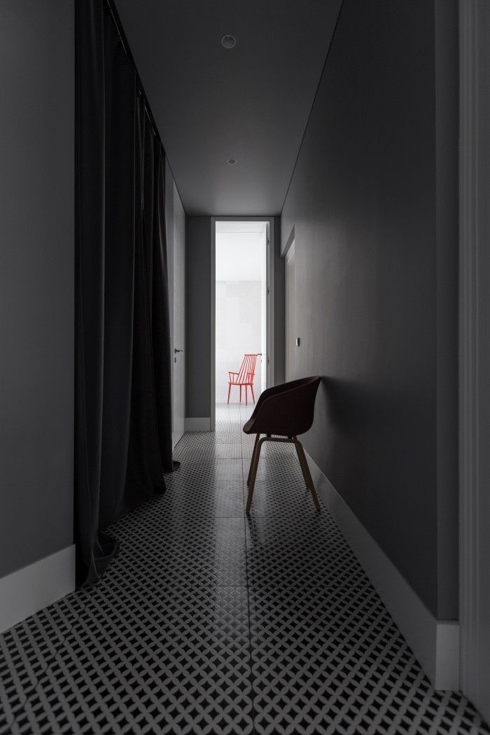 decoration couloir long et étroit sobre et sophistiqué au sol en vinyle graphique noir et blanc qui donne sur une pièce à vivre blanche 