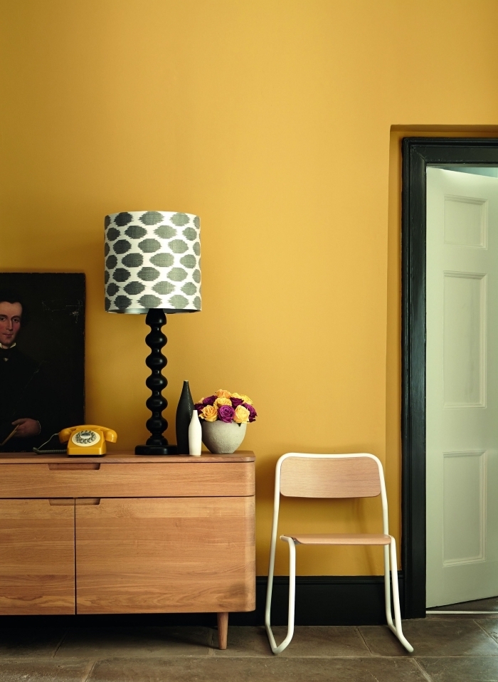 idée deco jaune moutarde dans un salon aux murs jaune, meubles salon de bois clair, modèle lampe blanc et gris foncé