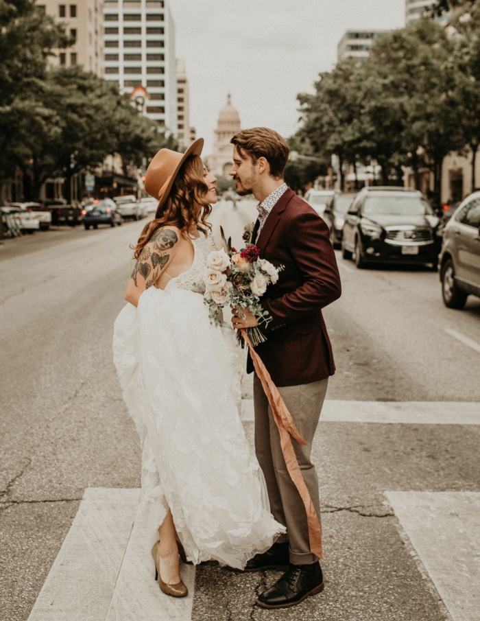 robe de mariée chic, chapeau feutre, veste homme bordeaux, bouquet de roses, tatouage femme, tenue de mariage vintage
