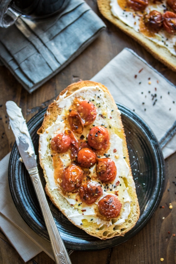 tranches de pain grillées tartinées de mascarpone avec des tomates cerises sautées arrosées d'huile d'olive