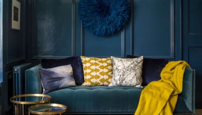 salon foncé avec canapé en velours, modèle de suspension murale bleu marine, accessoires de couleur moutarde