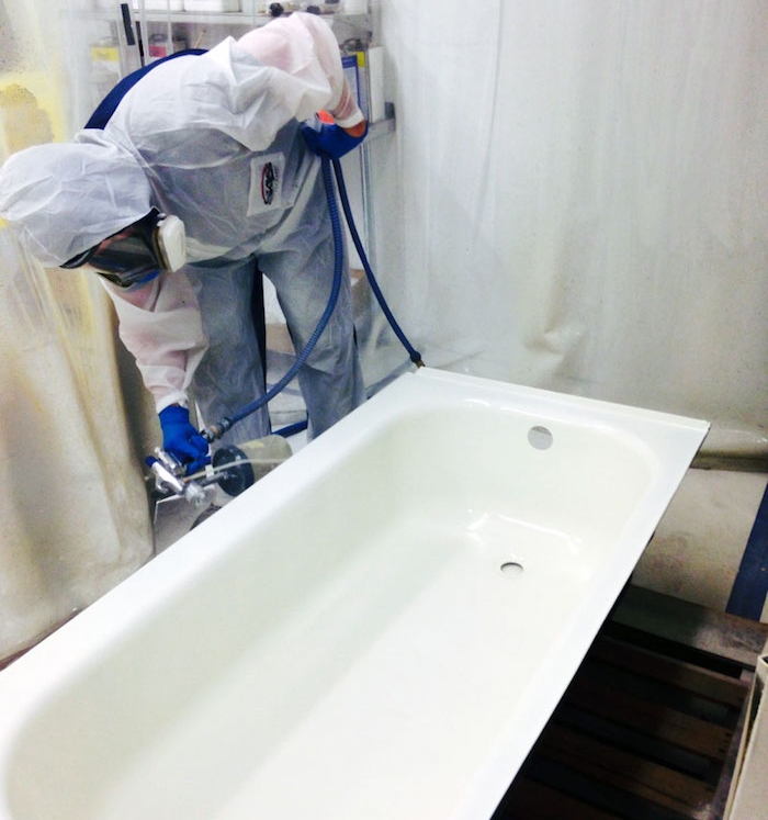 photo dun ouvrier peintre en train de repeindre une baignoire au pistolet dans un atelier