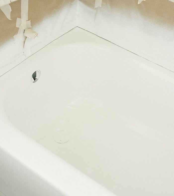 photo d une baignoire en train d être repeinte en blanc avec protection sur les murs