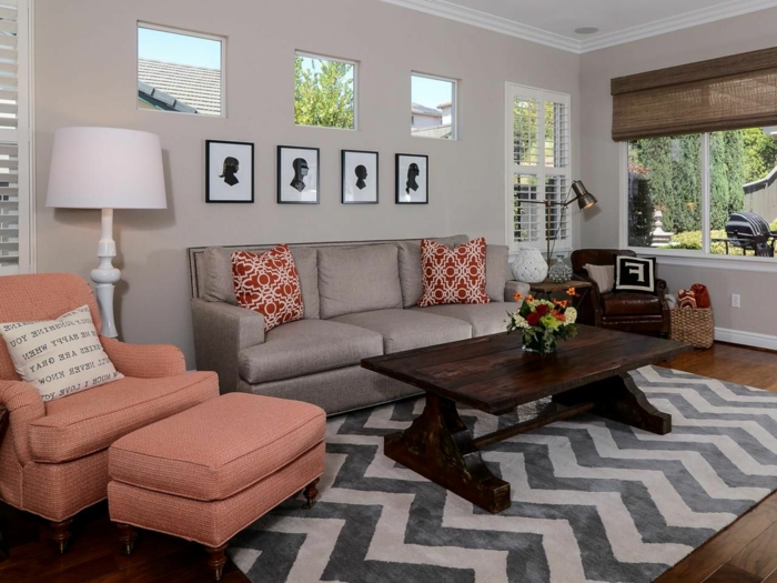 tapis géométrique, table vintage en bois, lampe de sol blanche, petites fenêtres, fauteuil rose orange