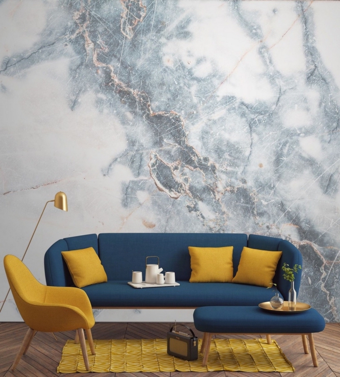 design intérieur moderne, décoration salon aux murs à effet marbre aux accents cuivrés, modèle de canapé bleu marine avec objet déco moutarde