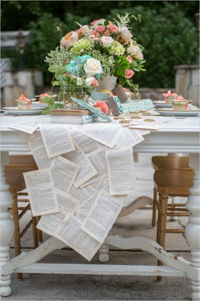 decoration table mariage originale, plusieurs feuilles de livre attachées, grand bouquet multicolore de roses, table blanche 