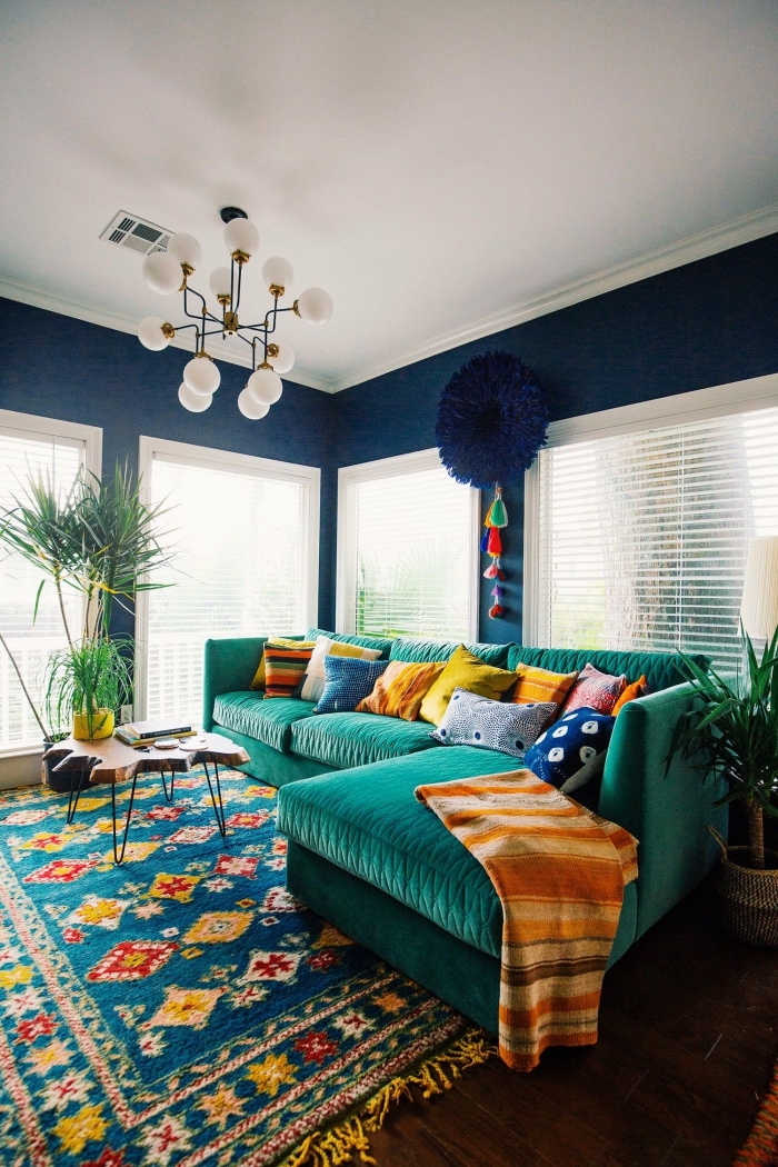 ambiance ethnique dans un salon bleu foncé aménagé avec canapé d'angle turquoise et accessoires en couleurs jaune et bleu