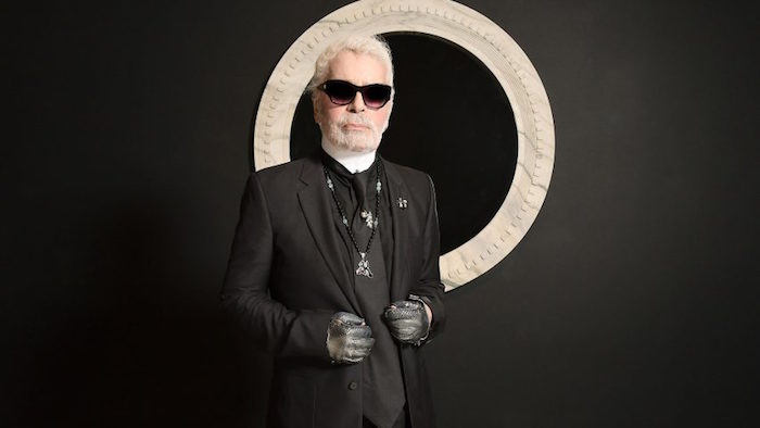 photo du créateur Chanel Karl Lagerfeld dans son costume noir avec catogan et lunettes noires sur fond noirn décédé à l'age de 85 ans