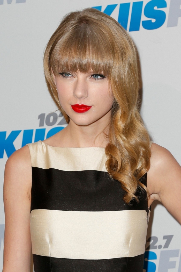 les cheveux de Taylor Swift, lèvres rouges, robe en noir et beige, cheveux bouclés blond miel