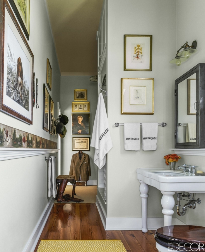 vasque pied blanche, sol en bois, plusieurs peintures encadrées, peinture toilette gris clair