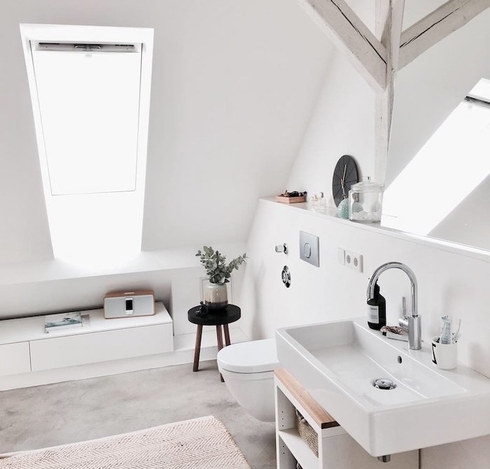 modele salle de bain sous comble avec vasque blanc, poutres apparentes blanchies, murs blancs et fenêtres de toit