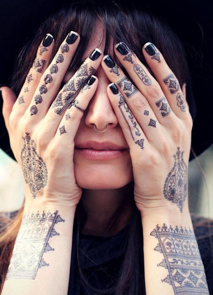 de l'art corporel avec un tatouage sur les doigts au henné noir aux motifs orientaux traditionnels