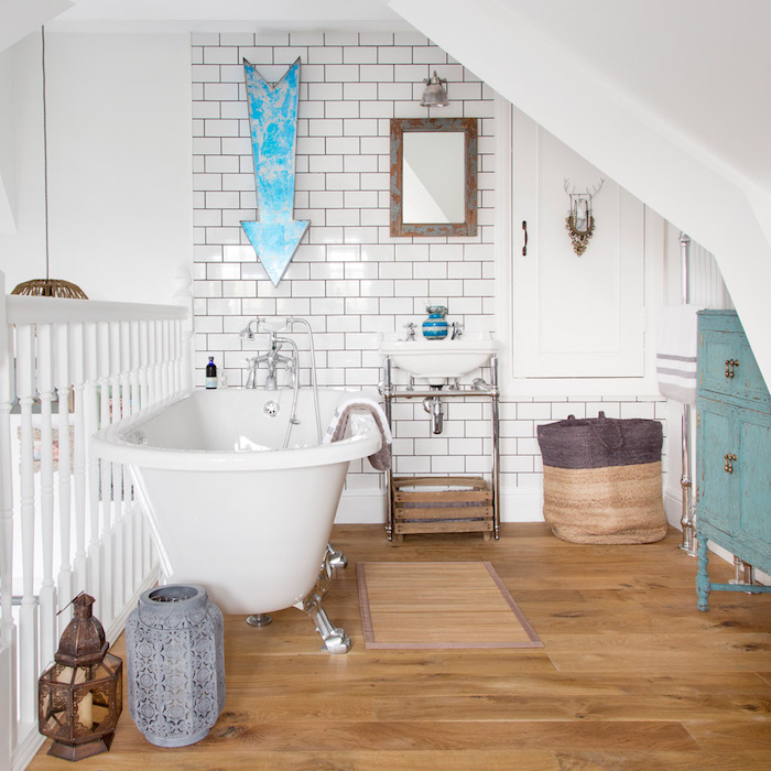 aménagement petite salle de bain mezzanine avec baignoire blanche sur parquet, meuble salle de bain bleu chine, lavabo console contre mur carrelage blanc