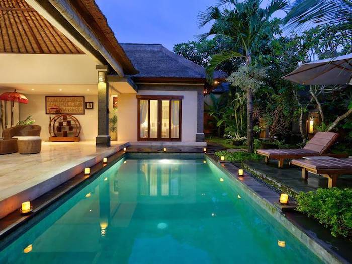 Maison luxueuse avec belle piscine individuelle, chaise longues et palmiers 