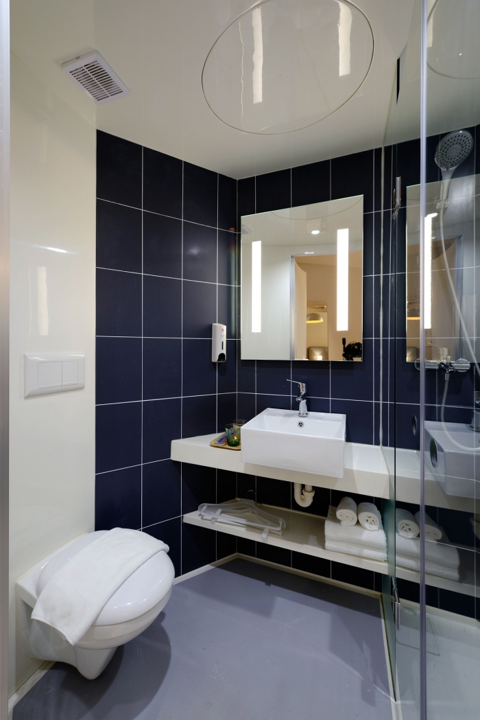 petite salle de bains qui combine une revêtement mural en pvc à finition brillante et des carreaux grands formats en bleu foncé