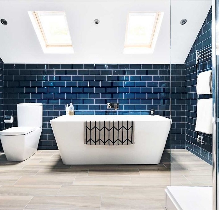 carrelage bleu nuit dans une salle de bain en blanc et bleu, baignoire et wc blanc, carrelage imitation parquet, douche avec paroi vitré