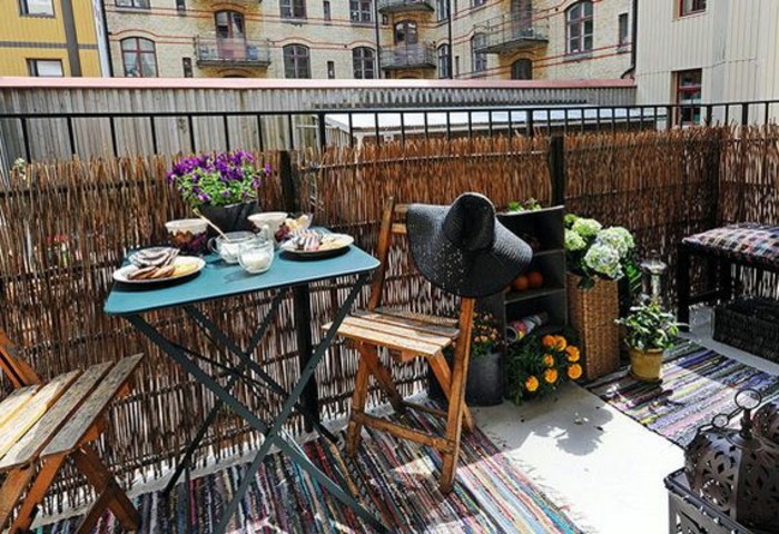 exemple amenagement petite terrasse avec brise vue vegetale, chaises de bois pliantes, table pliante metallique, plusieurs plantes fleuries