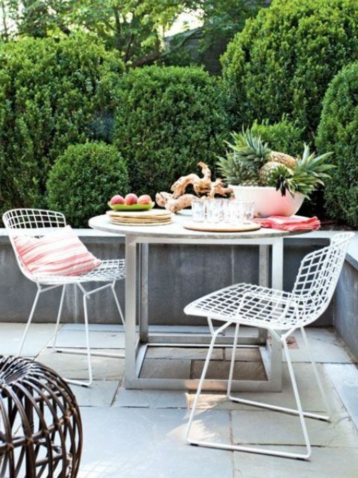 table metallique et chaises blanches metalliques dans une terrasse en beton avec vue sur un jardin végétalisé, terrasse design