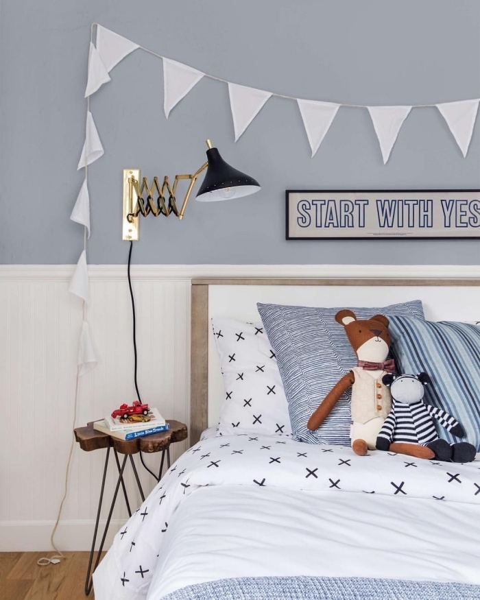 lambris blanc en tête de lit dans la chambre d'enfant en contraste léger avec le mur bleu gris, habiller un mur avec du lambris posé à la mi-hauteur