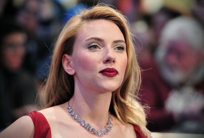 Scarlett Jonasson avec un blond californien, collier pierres précieuses, robe rouge, ombres à paupières bleues