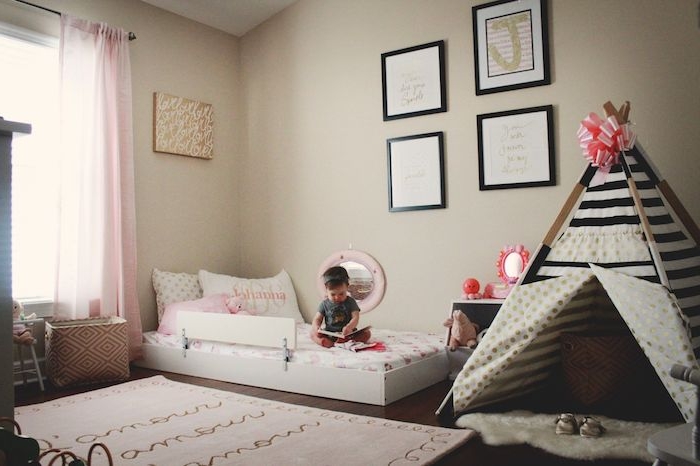 idee deco chambre bebe fille selon la méthode montessori avec murs beiges, tipi fille en noir et blanc avec ruban en top, lit au sol blanc, cadres decoratifs