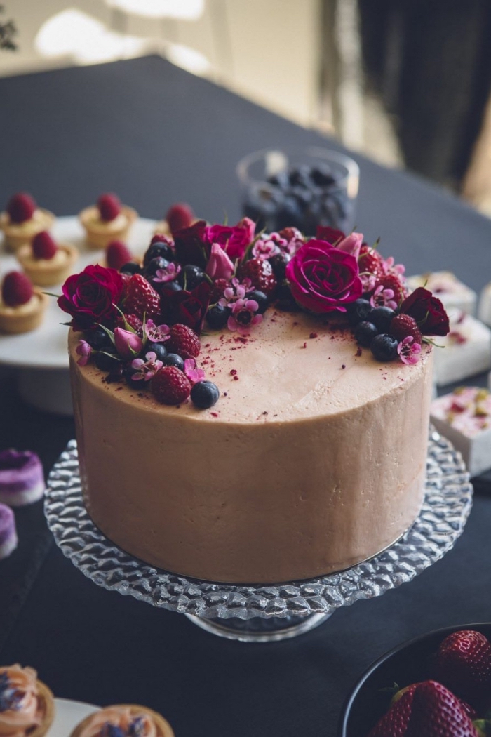 gateau anniversaire simple et beau au glaçage chocolat lisse sublimé par un joli décor de fleurs et de fruits rouges