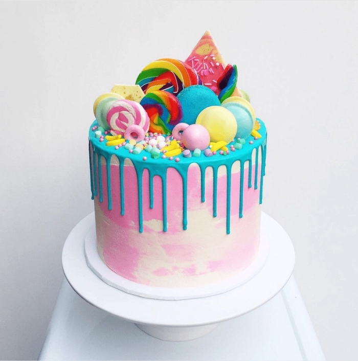 gâteau d'anniversaire au glaçage coulant bleu décoré de toutes sortes de bonbons, soucoupes acidulées, sucettes et perles en sucre