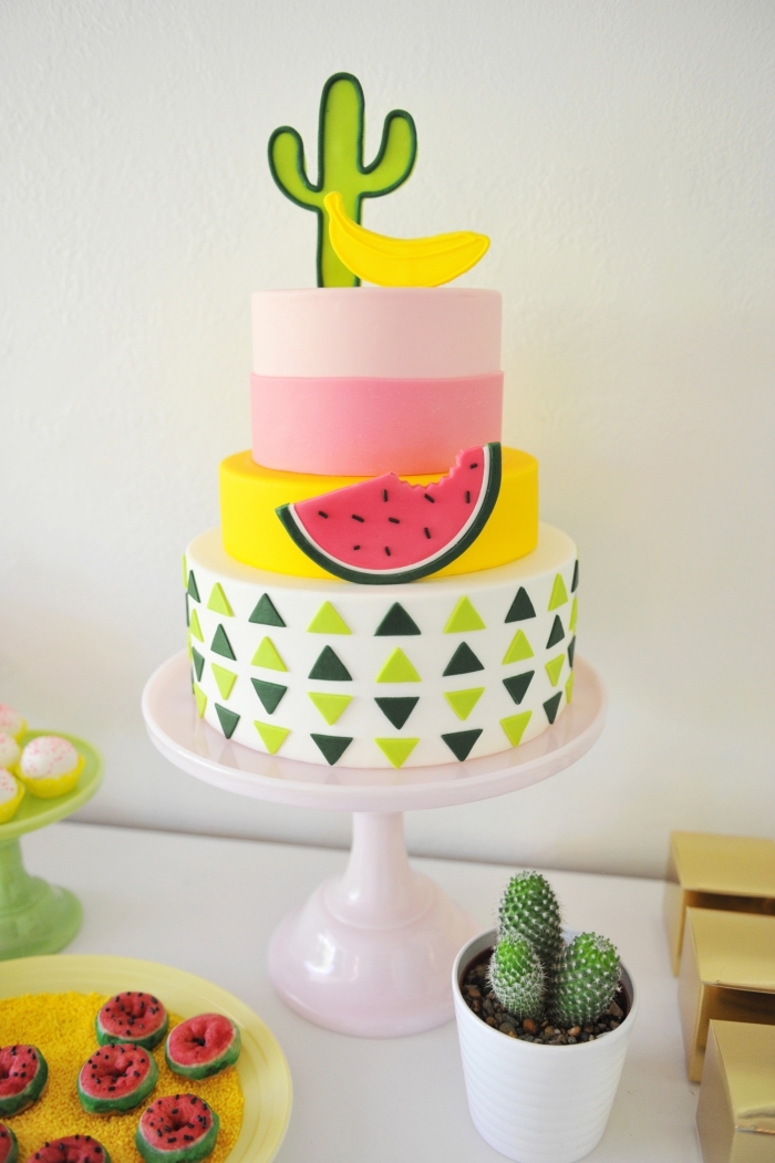 gâteau d'anniversaire étagé recouvert de pâte à sucre multicolore orné de petites décorations à motifs tropicaux